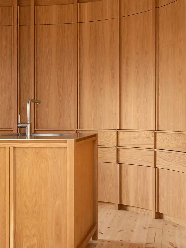 Kjøkkenet K05 med nærbilde av kjøkkenøy i eik og rustfritt stål, med et storslått bueskap i bakgrunnen